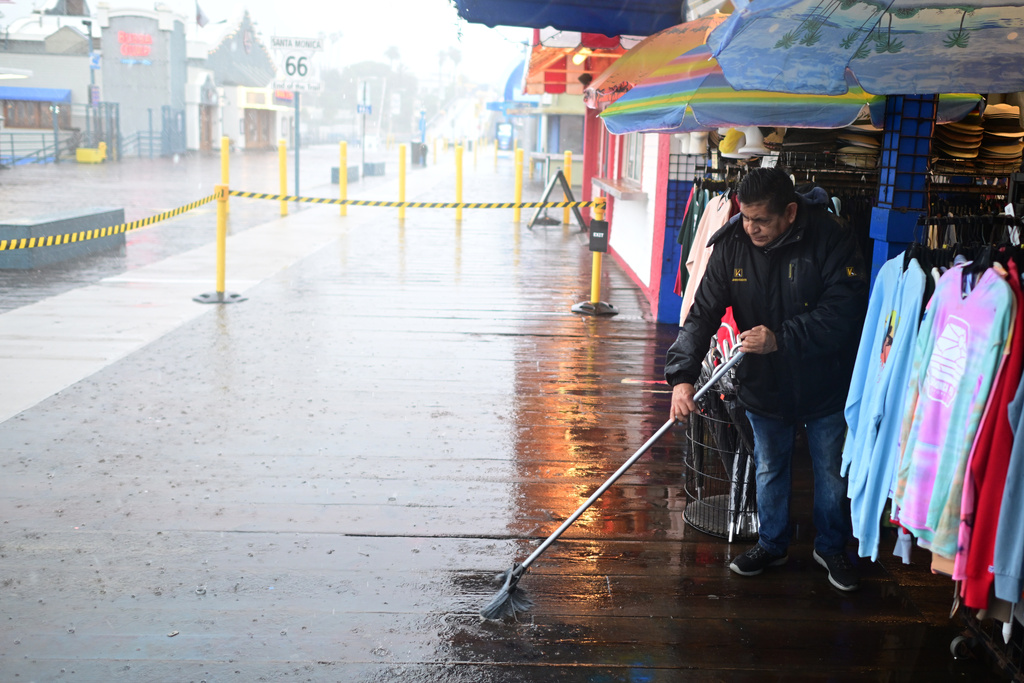 Miguel Lopez sweeps water from Marlene's Beachcomber on the Santa Monica pier Wednesday, Dec. 24, 2025, in Santa Monica, Calif. (AP Photo/Wally Skalij)