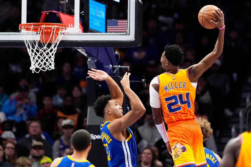 Charlotte Hornets forward Brandon Miller dunks over Golden State Warriors forward Trayce Jackson-Davis during the first half of an NBA basketball game, Wednesday, Dec. 31, 2025, in Charlotte, N.C. (AP Photo/Chris Carlson)