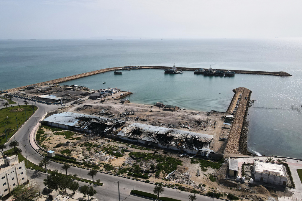 Backdropped by ships in the Strait of Hormuz, damage, according to local witnesses caused by several recent airstrikes during the U.S.-Israel military campaign, is seen on a fishing pier in the port of Qeshm island, Iran, Monday, April 13, 2026. (AP Photo/Asghar Besharati)