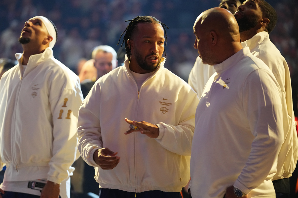 New York Knicks guard Jalen Brunson, center, shows his ring to his father Rick Brunson before an NBA basketball game between the New York Knicks and the Philadelphia 76ers Tuesday, Oct. 20, 2026, in New York. (AP Photo/Frank Franklin II)