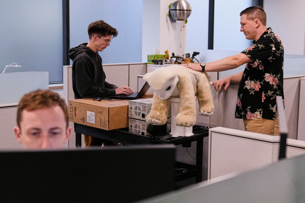 Software engineer Colin Soguero, standing at left, and creative director Morgan Pope, right, work on Familiar, an AI pet robot, prior to a demonstration at the Massachusetts-based startup Familiar Machines & Magic, Wednesday, April 29, 2026, in Woburn, Mass. (AP Photo/Charles Krupa)