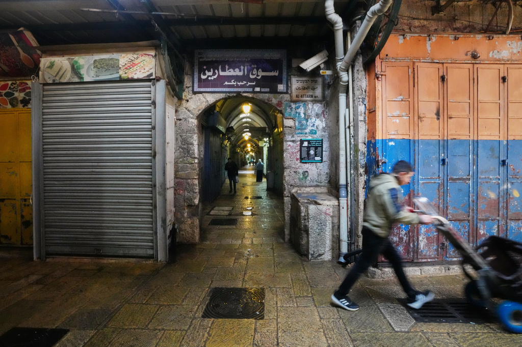A man pushes a handcart past closed shops in Jerusalem's Old City, Friday, March 27, 2026, as the area remains closed to visitors amid the war with Iran. (AP Photo/Mahmoud Illean)