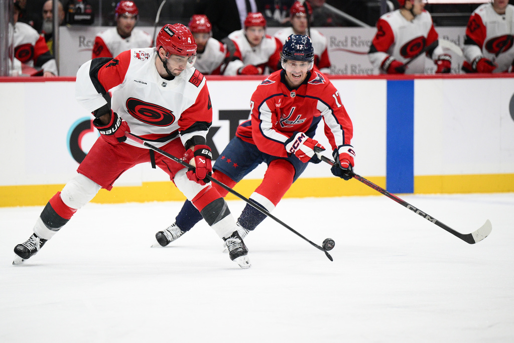 Carolina Hurricanes defenseman Shayne Gostisbehere (4) and Washington Capitals center Dylan Strome (17) battle for the puck during the first period of an NHL hockey game, Thursday, Dec. 11, 2025, in Washington. (AP Photo/Nick Wass)
