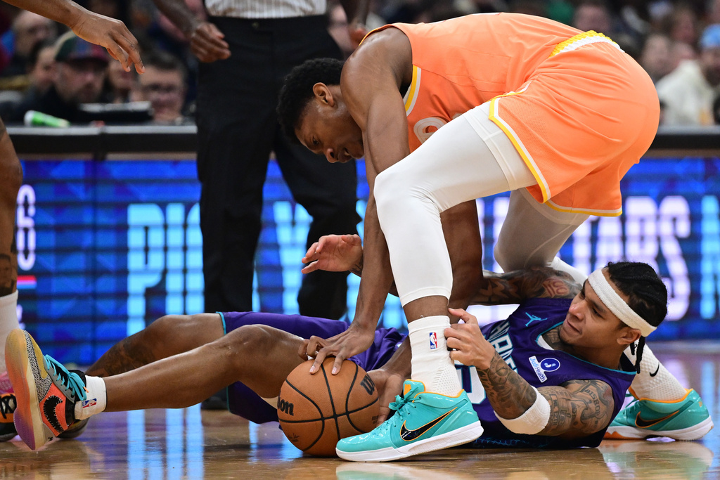 Cleveland Cavaliers forward De'Andre Hunter and Charlotte Hornets guard Tre Mann wrestle for a loose ball in the first half of an NBA basketball game, Monday, Dec. 22, 2025, in Cleveland. (AP Photo/David Dermer)