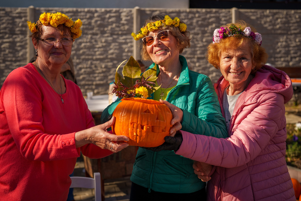 Women pose with a Halloween pumpkin they carved during an event at the Salcetului day care for the elderly state facility in Bucharest, Romania, Friday, Oct. 31, 2025. (AP Photo/Vadim Ghirda)