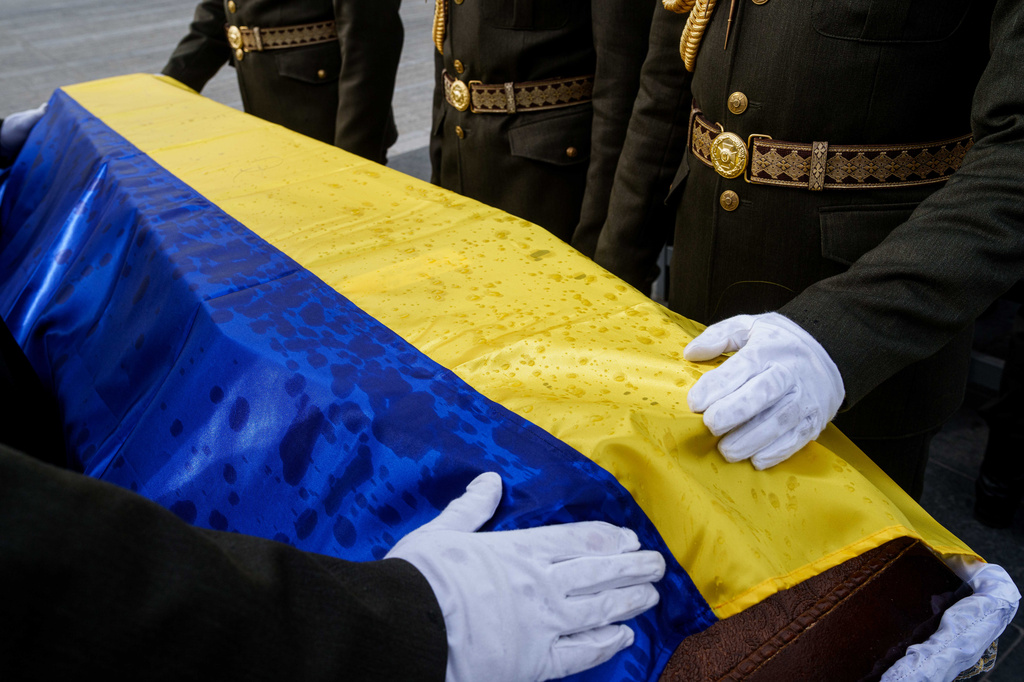 An honor guard straightens out the flag draped over the coffin of a unidentified Ukrainian soldier killed in battle during the Russian-Ukrainian war, during a funeral ceremony at a military cemetery near Kyiv, Ukraine, Thursday, April 30, 2026. (AP Photo/Evgeniy Maloletka)