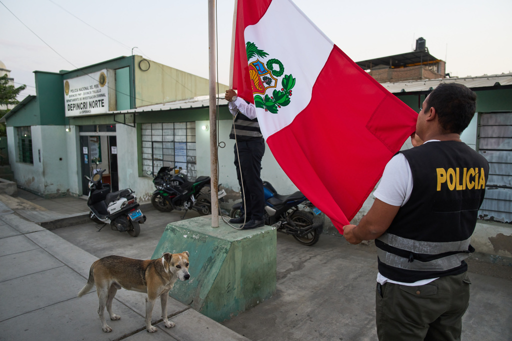 Police officers raise the Peruvian flag outside a criminal investigations unit in Trujillo, Peru, Monday, May 25, 2026. (AP Photo/Rodrigo Abd)