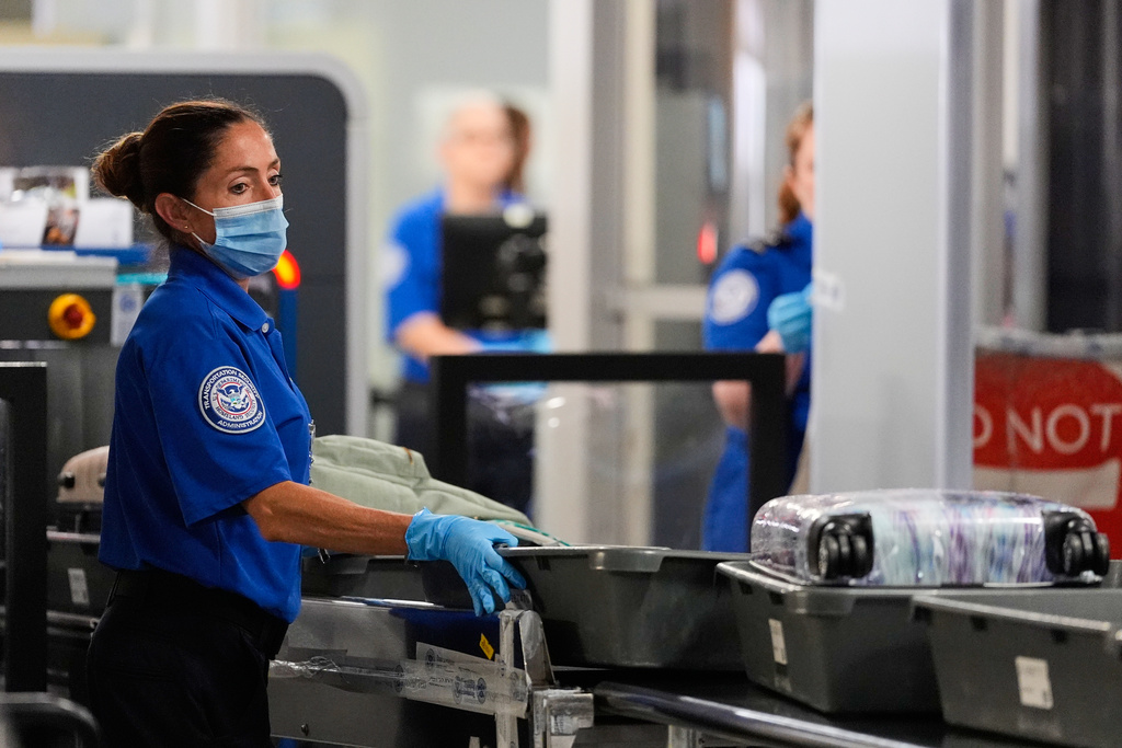 A TSA agent pushes bins along at a security checkpoint at the Dallas Fort Worth International Airport, at DFW Airport, Texas, Friday, Nov. 21, 2025. (AP Photo/Tony Gutierrez)