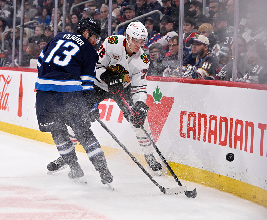 Chicago Blackhawks' Alex Vlasic (72) passes the puck past Winnipeg Jets' Gabriel Vilardi (13) during the second period of their NHL hockey game in Winnipeg, Tuesday March 3, 2026. (Fred Greenslade/The Canadian Press via AP)