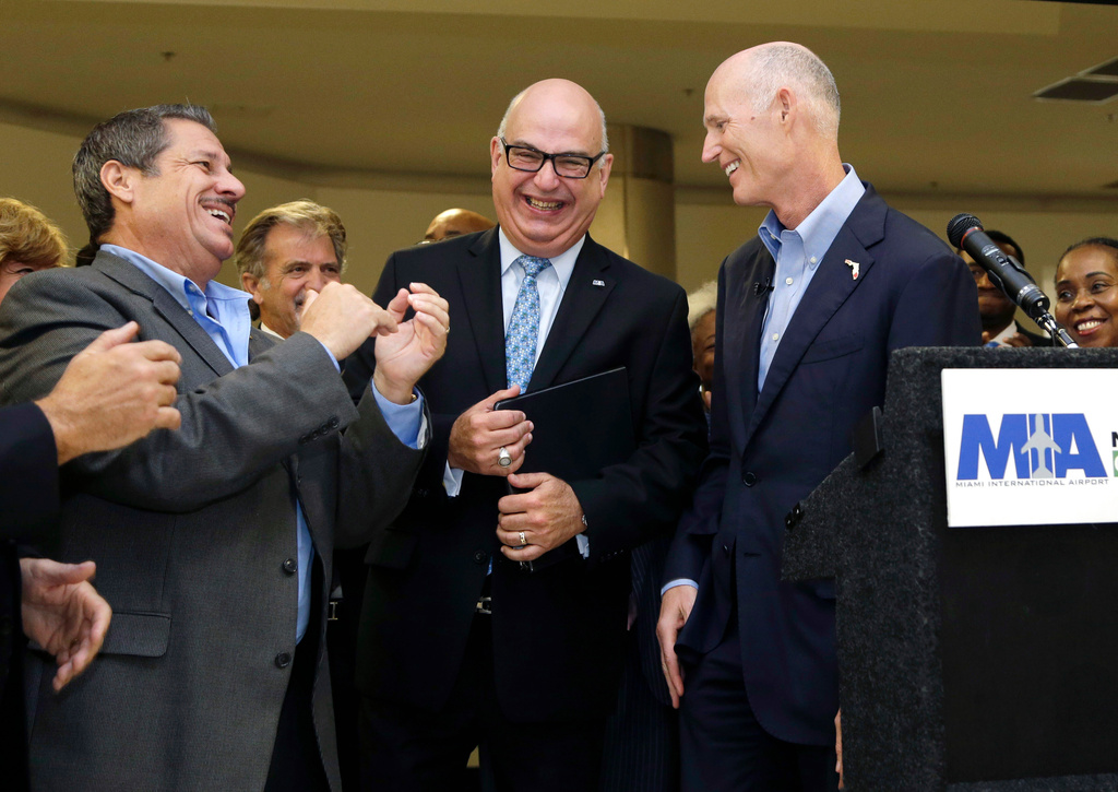 FILE - Florida Gov. Rick Scott, right, laughs with Emilio Gonzalez, director and chief executive officer of the Miami-Dade Aviation Department, center, and Jose "Pepe" Diaz, Miami-Dade County commissioner, left, after a news conference at Miami International Airport, Wednesday, Aug. 19, 2015, in Miami. (AP Photo/Lynne Sladky, File)