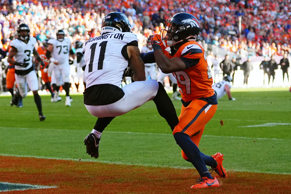 Jacksonville Jaguars wide receiver Parker Washington (11) scores a touchdown against Denver Broncos cornerback Ja'Quan McMillian, right, during the first half of an NFL football game in Denver, Sunday, Dec. 21, 2025. (AP Photo/Jack Dempsey)