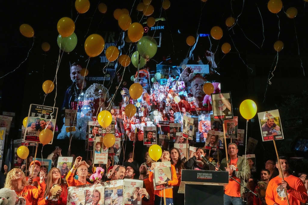 Balloons are released to mark the second birthday of hostage Kfir Bibas as demonstrators hold portraits of hostages held by Hamas in the Gaza Strip during a protest calling for their immediate release in Tel Aviv, Israel, Saturday Jan. 18, 2025. (AP Photo/Ohad Zwigenberg)