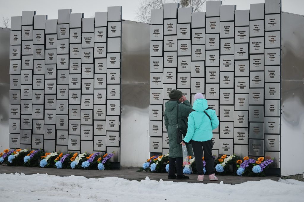 Relatives of those killed during the Russian occupation stand near the Wall of Remembrance during a ceremony to mark the fourth anniversary of the Russian invasion of Ukraine, in Bucha, Ukraine, Tuesday, Feb. 24, 2026. (AP Photo/Sergei Grits)