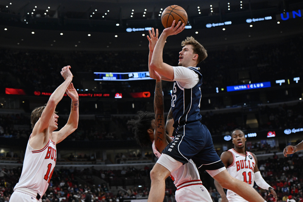 Dallas Mavericks' Cooper Flagg goes up for a shot against Chicago Bulls' Coby White and Matas Buzelis (14) during the first half of an NBA basketball game, Saturday, Jan. 10, 2026, in Chicago. (AP Photo/Paul Beaty)