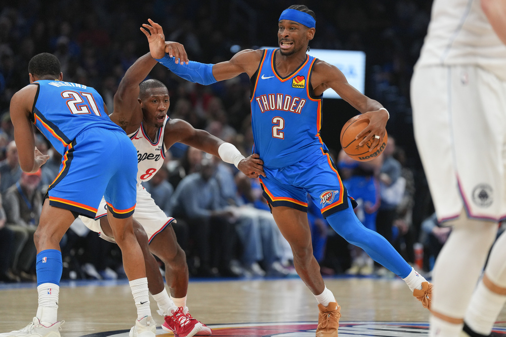 Oklahoma City Thunder guard Aaron Wiggins (21) screens Los Angeles Clippers guard Kris Dunn (8) as Thunder guard Shai Gilgeous-Alexander (2) pushes downcourt during the first half of an NBA basketball game, Thursday, Dec. 18, 2025, in Oklahoma City. (AP Photo/Kyle Phillips)