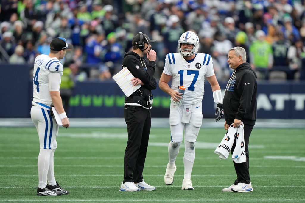 Indianapolis Colts quarterback Philip Rivers (17) talks with head coach Shane Steichen, second from left, during a time out in the first half of an NFL football game against the Seattle Seahawks, Sunday, Dec. 14, 2025, in Seattle. (AP Photo/Stephen Brashear)