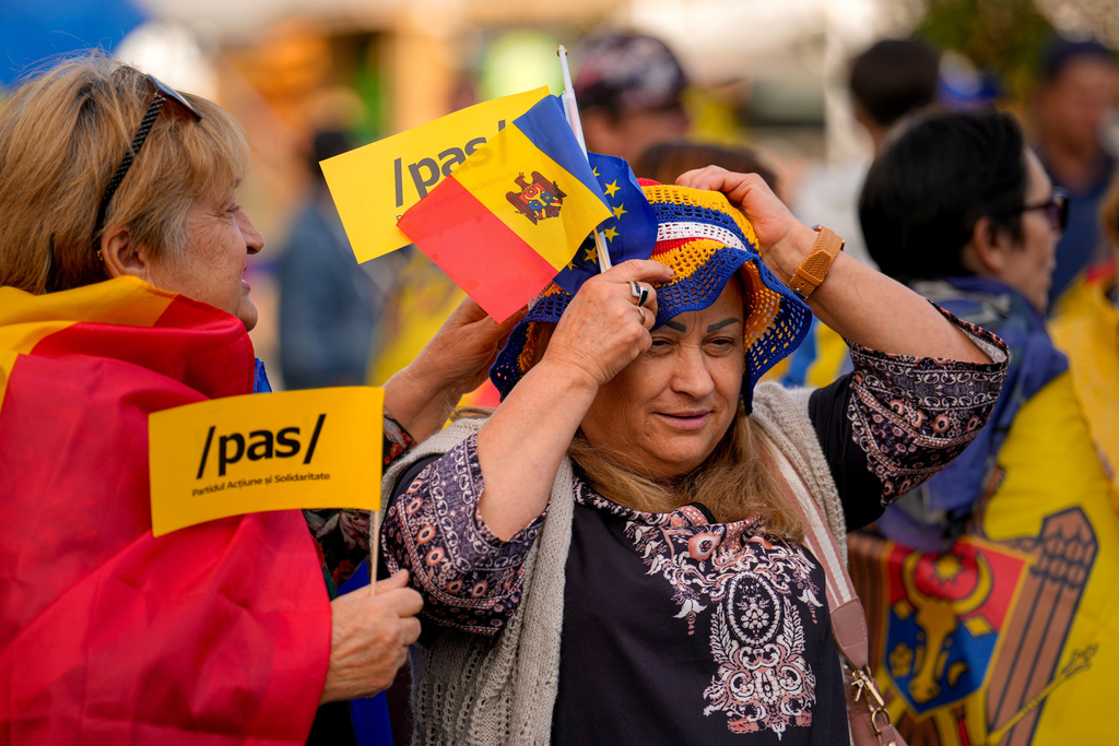 A woman holding Moldovan and EU flags adjusts her hat during a pro-EU rally of the ruling Party of Action and Solidarity (PAS), in Chisinau, Moldova, Friday, Sept. 26, 2025, ahead of parliamentary elections taking place on Sept. 28. (AP Photo/Vadim Ghirda)