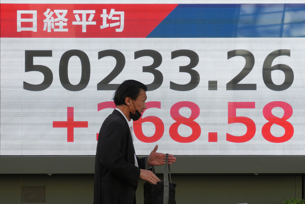 A person walks in front of an electronic stock board showing Japan's Nikkei index at a securities firm Thursday, Dec. 4, 2025, in Tokyo. (AP Photo/Eugene Hoshiko)