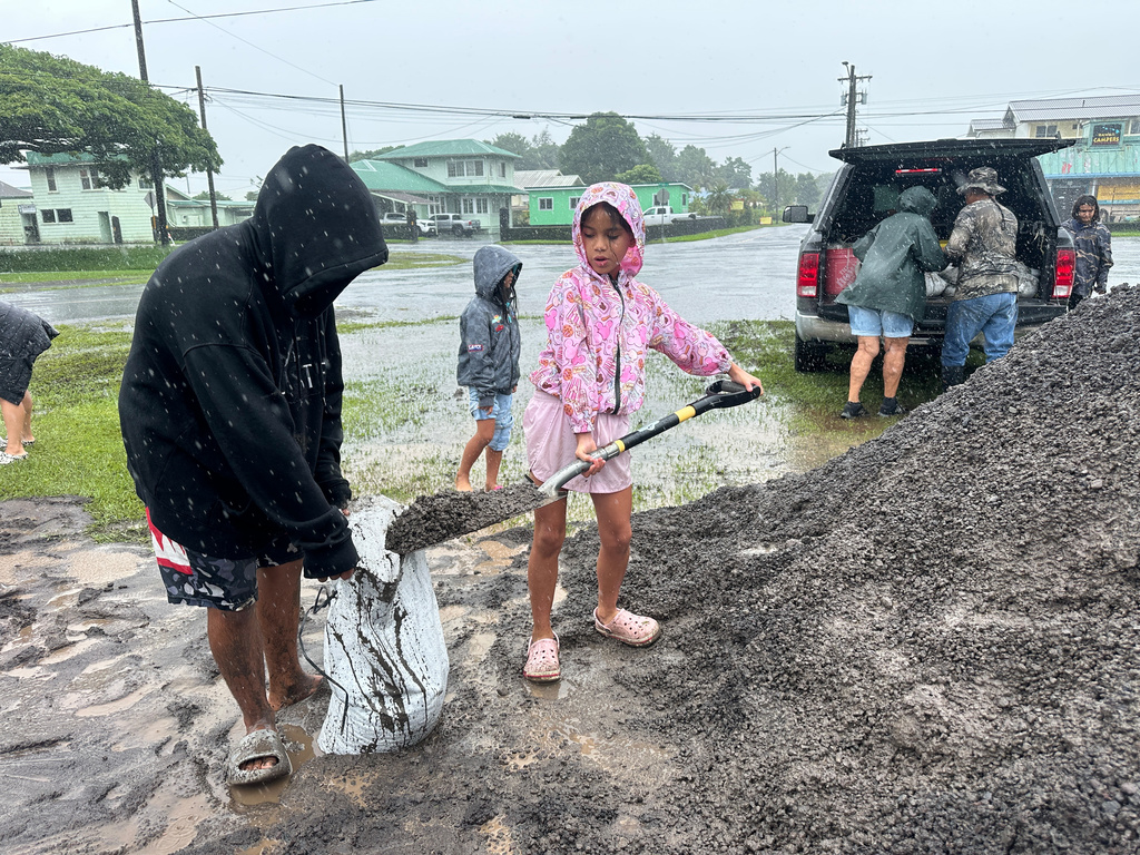 Kenzielynn Kekoa, center, of Hilo, Hawaii, helps her family fill sand bags as Hurricane Nolo sits nearby Friday, Sept. 25, 2026, in Hilo, Hawaii. (AP Photo/Eugene Garcia)