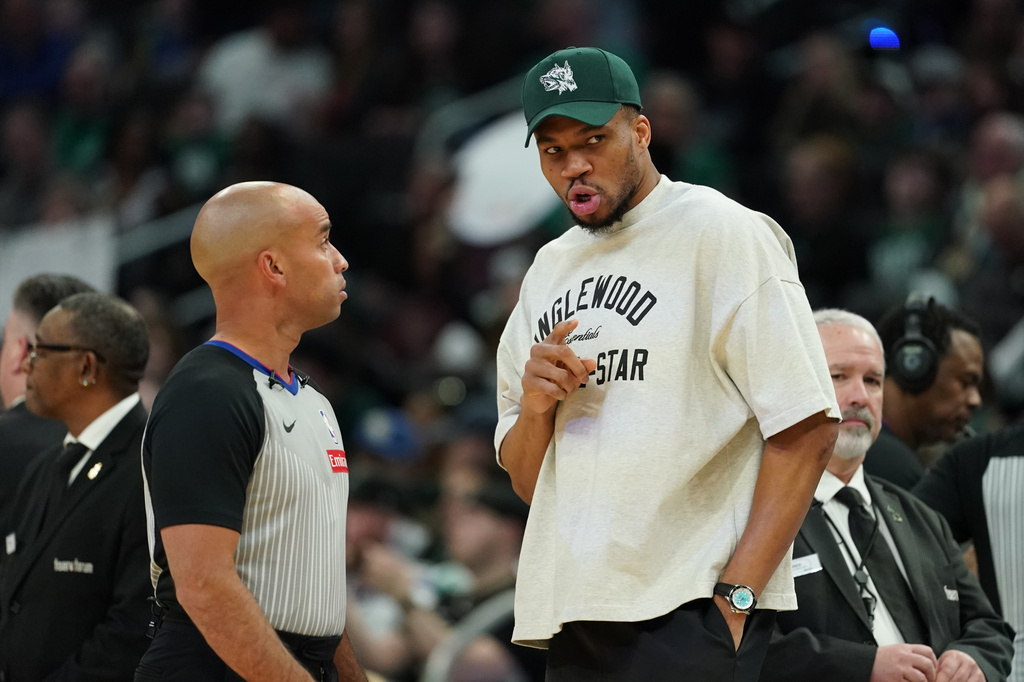 Injured Milwaukee Bucks' Giannis Antetokounmpo, center right, talks with an official, center left, during the first half of an NBA basketball game against the Boston Celtics, Friday, April 3, 2026, in Milwaukee. (AP Photo/Aaron Gash)