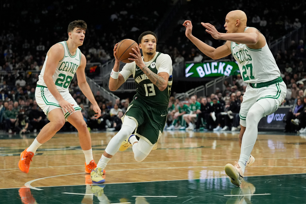 Milwaukee Bucks' Ryan Rollins (13) drives to the basket between Boston Celtics' Jordan Walsh (27) and Hugo Gonzalez (28) during the first half of an NBA basketball game Thursday, Dec. 11, 2025, in Milwaukee. (AP Photo/Aaron Gash)