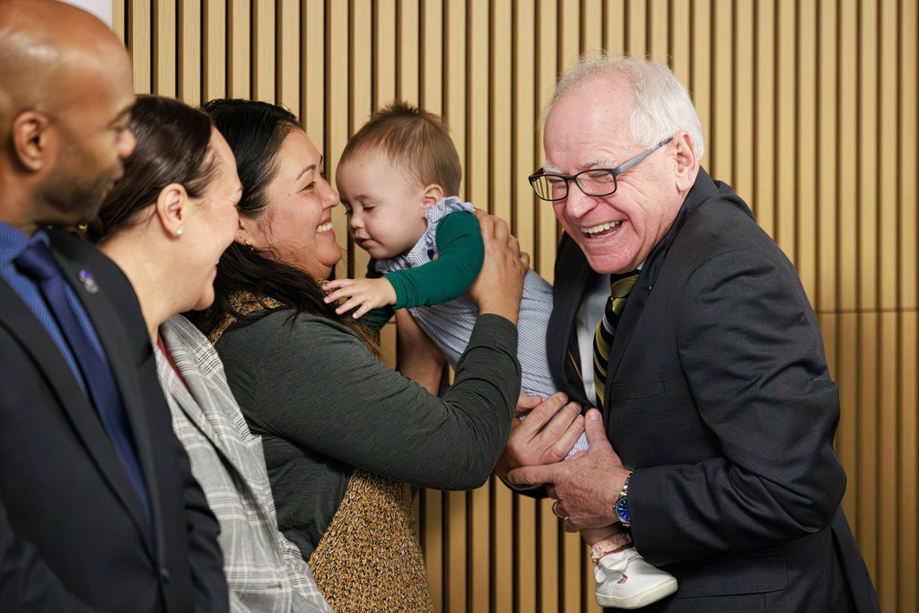 Gov. Tim Walz smiles at a child before speaking during a press conference on Tuesday, Jan. 6, 2026 at the Coliseum Building in Minneapolis. (Kerem Yücel/Minnesota Public Radio via AP)