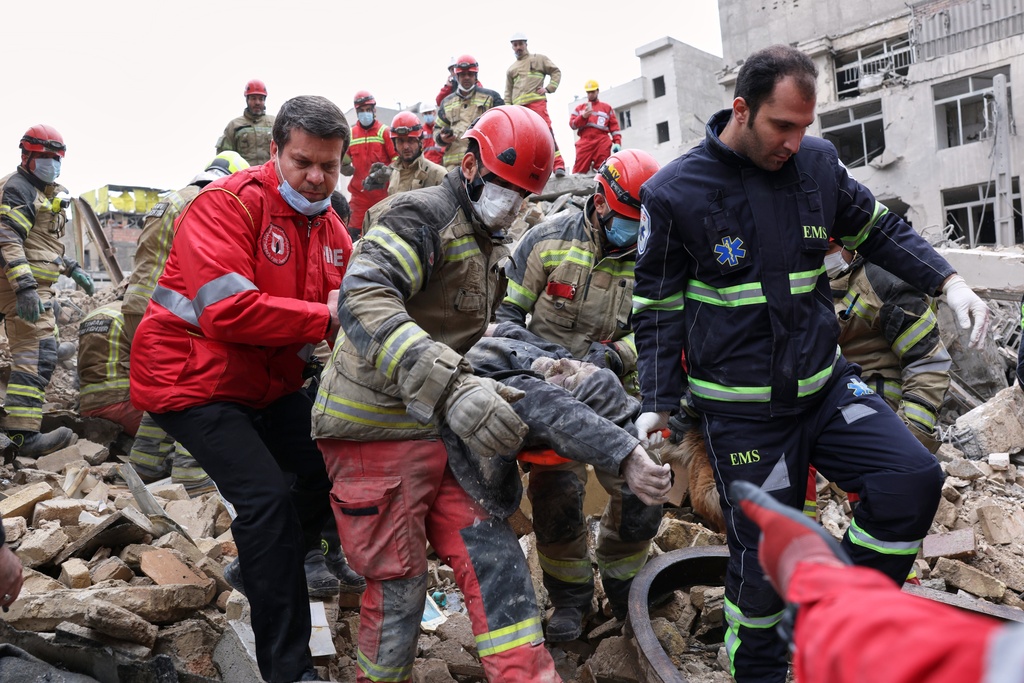 Rescue workers carry a severely injured man after pulling him from the rubble following a strike in southern Tehran, Iran, Friday, March 13, 2026. (AP Photo/Sajjad Safari)