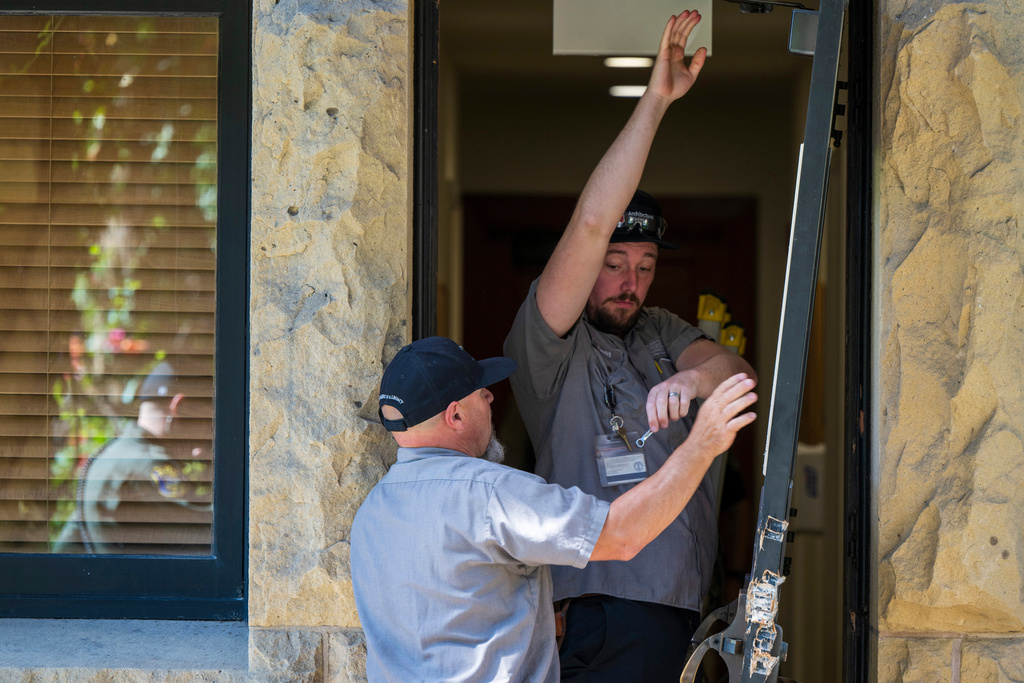 FILE - Campus maintenance workers repair a broken door at the office of the president at Stanford University in Palo Alto, Calif., June 5, 2024. (AP Photo/Nic Coury, File)