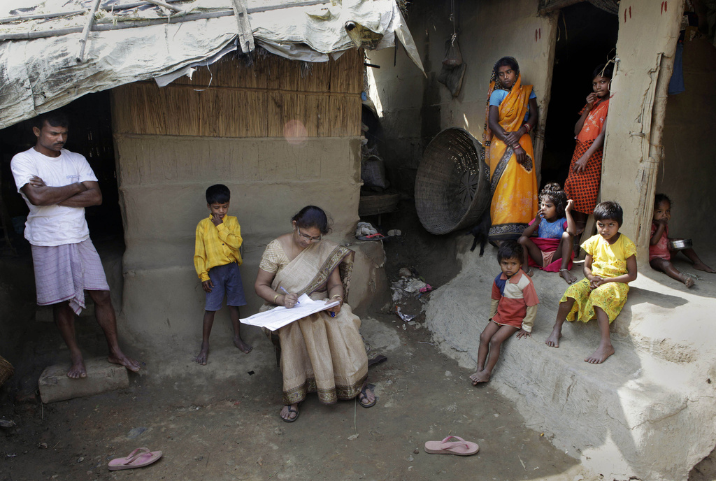 FILE -Mahesh Shah, left, stands as his family members look while census worker Rumima Das, writes the information on a paper on the first day of the national census at Ramsingh Chapori village, east of Gauhati, India, April 1, 2010. (AP Photo/Anupam Nath, File)