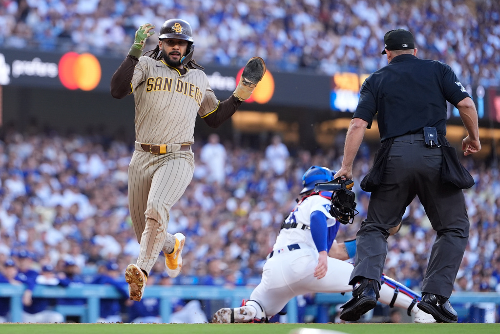 San Diego Padres' Fernando Tatis Jr., left, scores on a single by Gavin Sheets as Los Angeles Dodgers catcher Dalton Rushing, center, takes a late throw during the first inning of a baseball game Friday, July 3, 2026, in Los Angeles. (AP Photo/Mark J. Terrill)