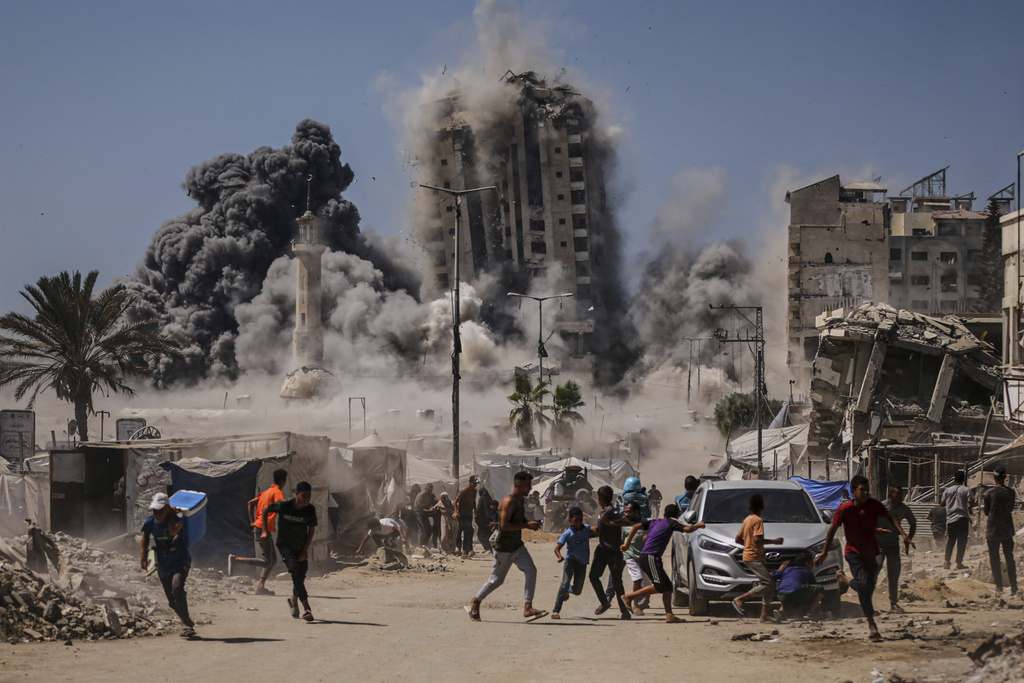 Palestinians run for cover during an Israeli airstrike on a high-rise building in Gaza City, Friday, Sept. 5, 2025, after the Israeli army issued a prior warning. (AP Photo/Yousef Al Zanoun)