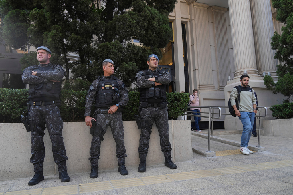 Police officers stand guard in front of a building during an operation investigating investment funds and the fuel sector, on Avenida Faria Lima, in Sao Paulo, Thursday, Aug. 28, 2025. (AP Photo/Andre Penner)