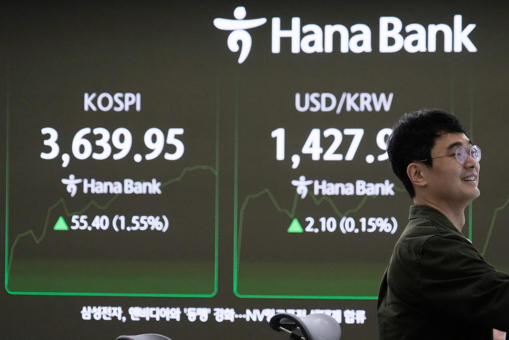 A currency trader watches monitors near a screen showing the Korea Composite Stock Price Index (KOSPI), left, and the foreign exchange rate between U.S. dollar and South Korean won at the foreign exchange dealing room of the Hana Bank headquarters in Seoul, South Korea, Tuesday, Oct. 14, 2025. (AP Photo/Ahn Young-joon)