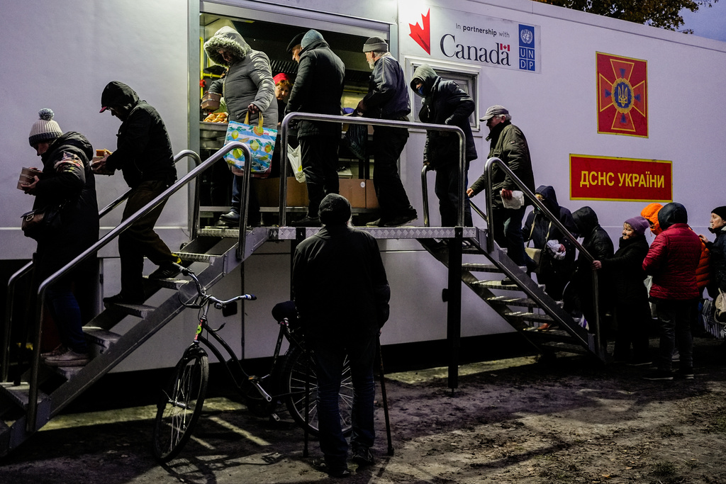 People receive free meals at a distribution point during a rolling blackout, Thursday, Oct. 16, 2025, in Shostka, Ukraine. (AP Photo/Julia Demaree Nikhinson)