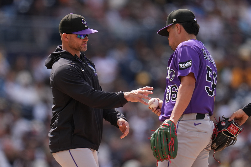 Colorado Rockies pitcher Valente Bellozo (56) hands the ball to manager Warren Schaeffer as he exits during the seventh inning of a baseball game against the San Diego Padres Sunday, April 12, 2026, in San Diego. (AP Photo/Gregory Bull)