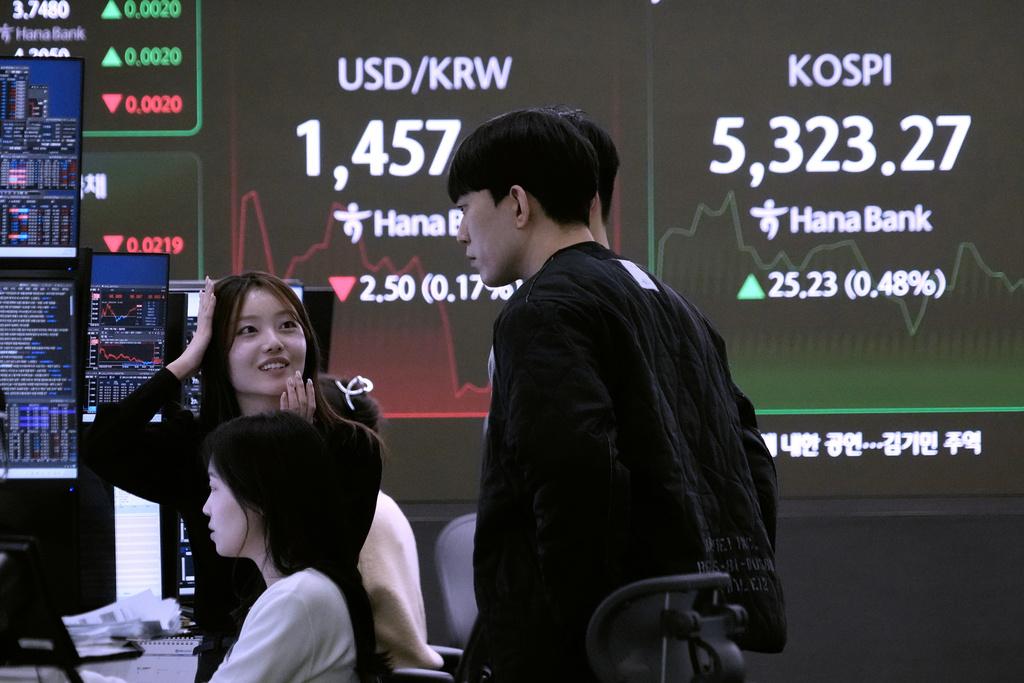Currency traders work near a screen showing the Korea Composite Stock Price Index (KOSPI), top right, and the foreign exchange rate between U.S. dollar and South Korean won at the foreign exchange dealing room of the Hana Bank headquarters in Seoul, South Korea, Tuesday, Feb. 10, 2026. (AP Photo/Ahn Young-joon)