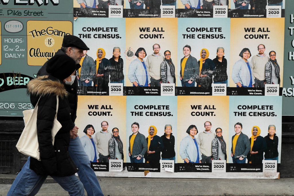 FILE - In this Wednesday, April 1, 2020 file photo,People walk past posters encouraging participation in the 2020 Census in Seattle's Capitol Hill neighborhood. (AP Photo/Ted S. Warren, File)
