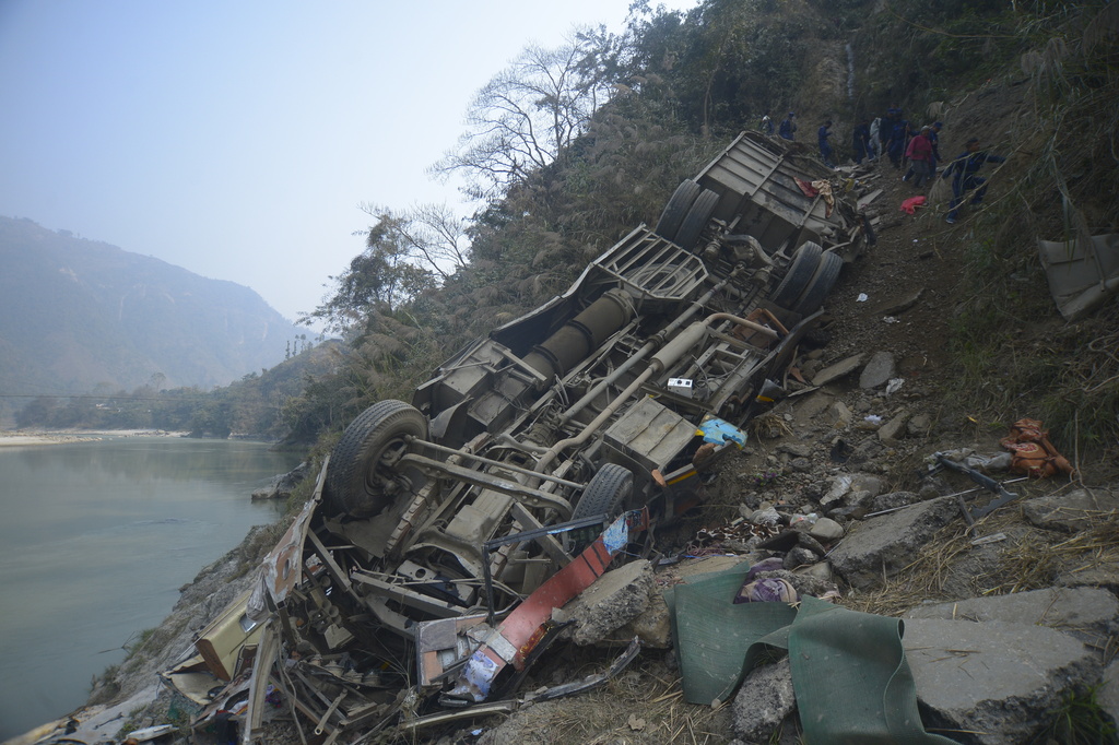 The wreckage of a bus lies on the bank of the Trishuli River after it drove off a mountain highway near Benighat, west of the capital Kathmandu, Nepal, Monday, Feb. 23, 2026. (AP Photo/Bijay Rai)