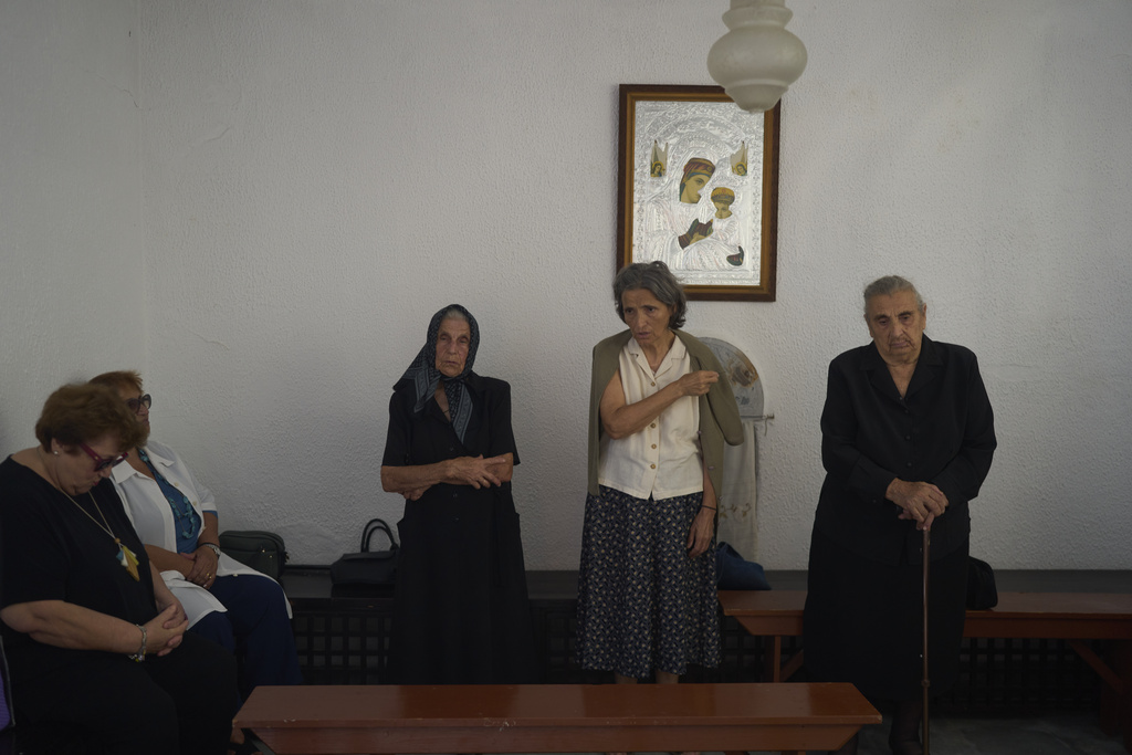Worshippers make the Sign of the Cross during a liturgy at the family-owned Agios Sostis chapel on the island of Tinos, Greece, Monday, Sept. 8, 2025. (AP Photo/Petros Giannakouris)