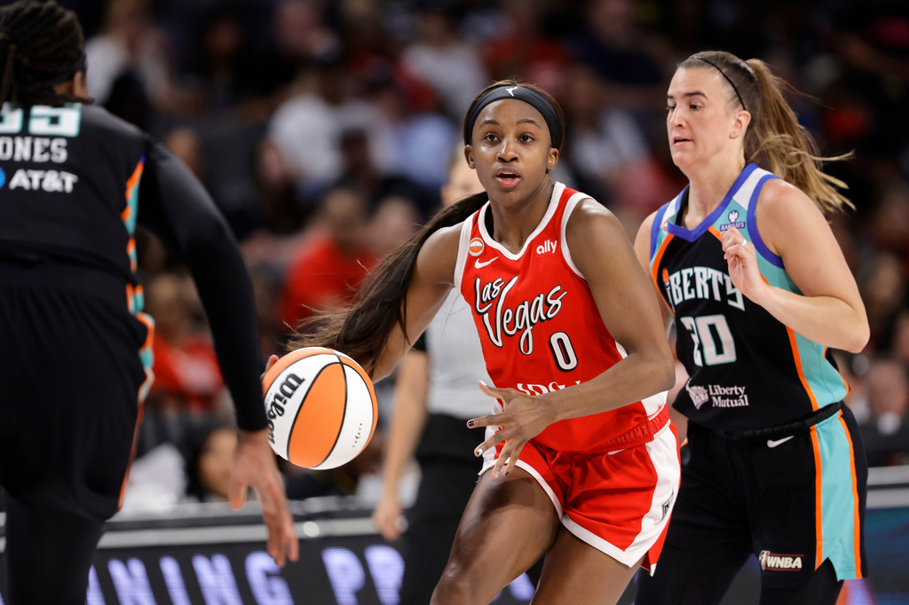 Las Vegas Aces guard Jackie Young (0) drives between New York Liberty center Jonquel Jones, left, and guard Sabrina Ionescu (20) during the first half of an WNBA basketball game Thursday, July 30, 2026, in Las Vegas. (Steve Marcus/Las Vegas Sun via AP)
