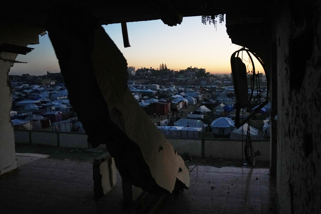 A makeshift tent camp for displaced Palestinians is seen through destruction in Deir al-Balah, central Gaza Strip, Wednesday, Nov. 26, 2025. (AP Photo/Abdel Kareem Hana)