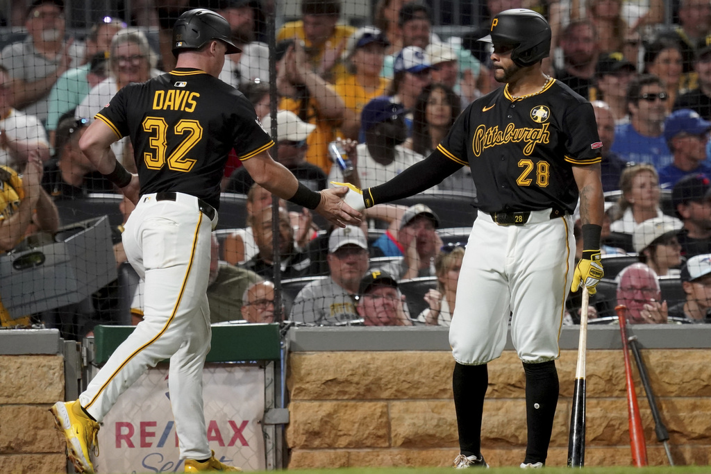 Pittsburgh Pirates' Henry Davis, left, is greeted by Tommy Pham, right, after scoring on a wild pitch during the seventh inning of a baseball game against the Toronto Blue Jays, Monday, Aug. 18, 2025, in Pittsburgh. (AP Photo/Matt Freed)