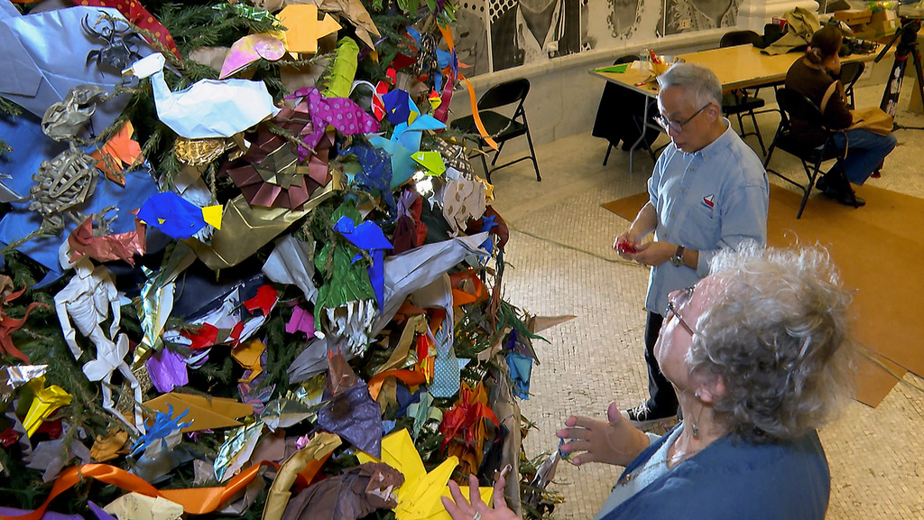Co-designers Talo Kawasaki and Rosalind Joyce decorate the Origami Holiday Tree at the American Museum of Natural History, Thursday, Nov. 13, 2025, in New York. (AP Photo/Joe Frederick)