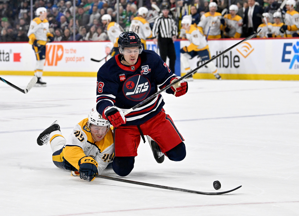 Nashville Predators' Reid Schaefer (49) reaches for the puck around Winnipeg Jets' Jacob Bryson (78) during the first period of their NHL hockey game in Winnipeg, Tuesday March 17, 2026. (Fred Greenslade/The Canadian Press via AP)
