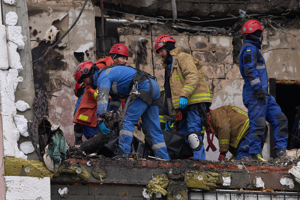 Rescuers put fragments of a body of the victim into a plastic bag after Russian drone hit a multi-storey apartment building during massive missile and drone attack in Kyiv, Ukraine, Saturday, Dec. 27, 2025. (AP Photo/Efrem Lukatsky)