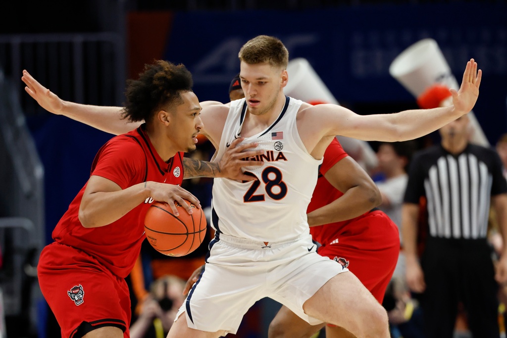 North Carolina State forward Darrion Williams, left, drives against Virginia forward Thijs de Ridder (28) during the first half of an NCAA college basketball game in the quarterfinals of the Atlantic Coast Conference tournament in Charlotte, N.C., Thursday, March 12, 2026. (AP Photo/Nell Redmond)