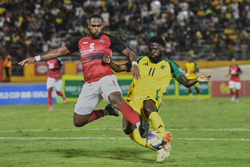 Trinidad and Tobago's Josiah Trimmingham, left, tackles Jamaica's Shamar Nicholson during a World Cup 2026 qualifying soccer match at the Independence Park stadium in Kingston, Jamaica, Tuesday, Sept. 9, 2025. (AP Photo/Collin Reid)