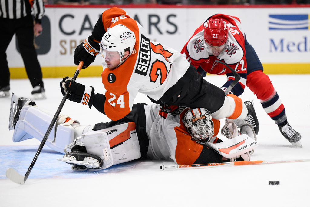 Philadelphia Flyers defenseman Nick Seeler (24) and goaltender Dan Vladar, bottom, battle for the puck against Washington Capitals right wing Brandon Duhaime (22) during the second period of an NHL hockey game, Wednesday, Feb. 25, 2026, in Washington. (AP Photo/Nick Wass)