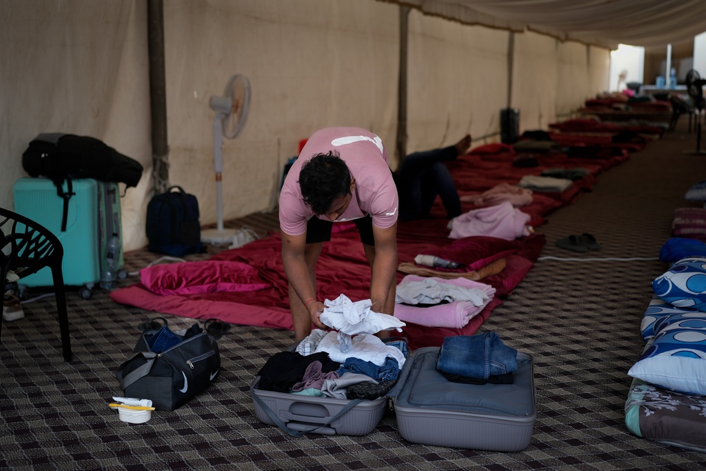 A stranded Indian traveler takes his clothes out of his suitcase after arriving at a farmhouse owned by an Indian businessman, now converted into a shelter in Ajman, near Dubai, United Arab Emirates, Saturday, March 7, 2026. (AP Photo/Altaf Qadri)
