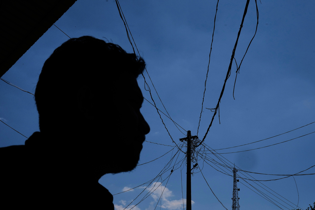 Safeer Mohammed Koorimannil looks at the maze of wires coming off a utility pole next to an internet tower outside his CM Fisheries office in Sulthan Bathery in the southern state of Kerala, India, Thursday, March 12, 2026. (AP Photo/Manish Swarup)
